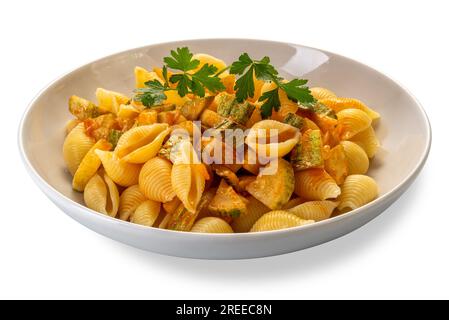 Pâtes Conchiglie rigate. Macaroni en forme de coquille striée avec courgette et sauce tomate avec feuilles de persil dans plat blanc isolé sur blanc avec cl Banque D'Images