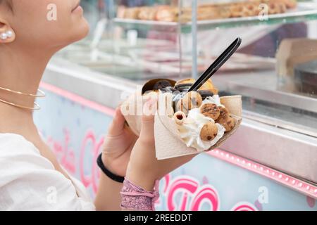 Fille après avoir reçu sa gaufre dans un stand de nourriture de rue. Banque D'Images