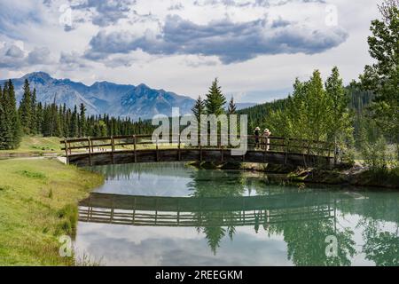 La fumée des nombreux feux de forêt provoque la brume sur les montagnes Rocheuses en arrière-plan. Passerelle au-dessus de Cascade Pond, Banff, Alberta, Canada Banque D'Images