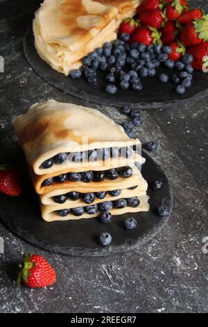 photo de crêpes frites avec des fraises mûres juteuses et des myrtilles sur une assiette gros plan Banque D'Images