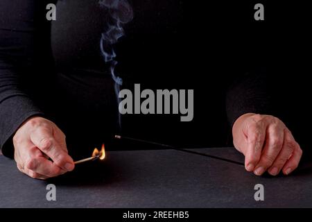 Mains de femmes allumant un bâton d'encens avec une allumette Banque D'Images