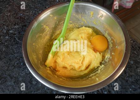 Cuisine souabe, préparation de pâte à choux pour les mini choux à la crème, ajout d'œufs à la pâte à choux crue, cuillère de cuisson, cuillère à remuer, remuer dans la casserole Banque D'Images