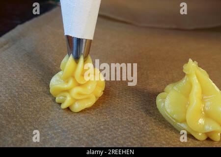 Cuisine souabe, préparation de mini-bouffées à la crème, presser la pâte à choux crue à travers un sachet à passepoil sur du papier sulfurisé, des échairs, des profiteroles, des pâtisseries bordées Banque D'Images