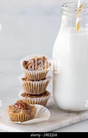 Gros plan d'une pile de tartes aux noix de pécan au caramel salé avec une bouteille de lait. Banque D'Images