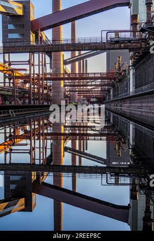 Cokerie de Zollverein à la mine de Zollverein, ponts à bande transporteuse, cheminées, batteries de fours à coke reflétées dans l'eau de pluie qui s'y est accumulée Banque D'Images