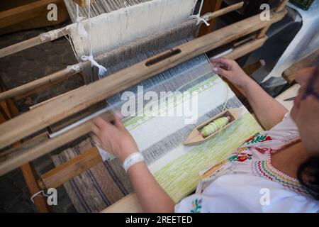 KEZMAROK, SLOVAQUIE - juillet 9, 2023 : artisan traitant le coton sur un métier à tisser traditionnel en bois au Festival européen du folklore et de l'artisanat à Kezmaro Banque D'Images