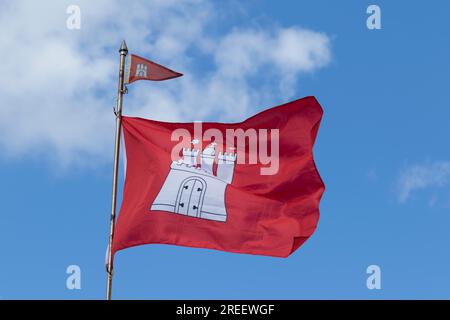 Drapeau rouge avec les armoiries de Hambourg contre un ciel bleu à Hambourg, Allemagne Banque D'Images