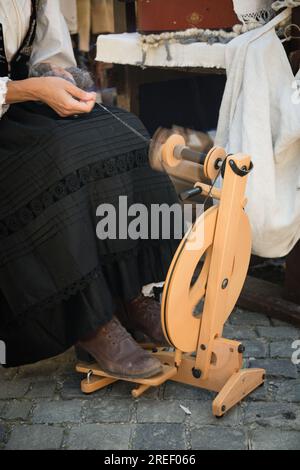 Artisan utilisant une roue de filature pour transformer la laine en fil Banque D'Images