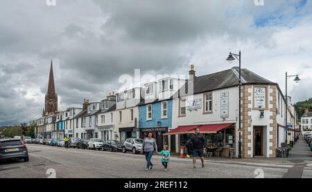 Une famille traversant la route principale (St MarySt) dans la ville de Kirkudbright, Dumfries et Galloway dans le sud-ouest de l'Écosse. Magasins et entreprises. Banque D'Images