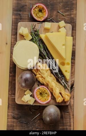 Fromage Mazdar, cubes de fromage gouda, fromage fumé chechil.fromage assorti sur une planche de bois avec des herbes et des fruits.fromages durs et mous, romarin et Banque D'Images