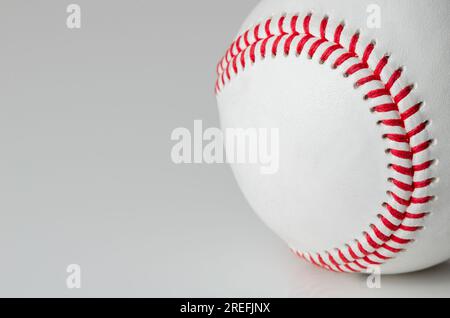 Gros plan d'une balle de baseball blanche avec des points rouges sur un fond blanc Banque D'Images