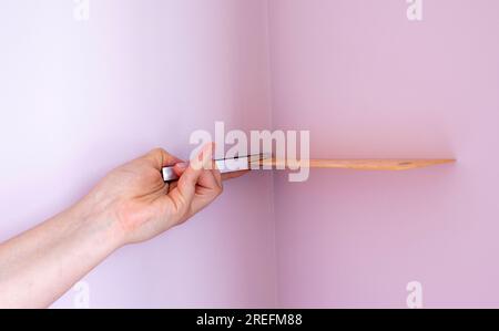 Le travailleur détient un coin métallique de mesure et mesure l'angle du mur. Finition du travail. Réparation dans l'appartement, bureau. Banque D'Images