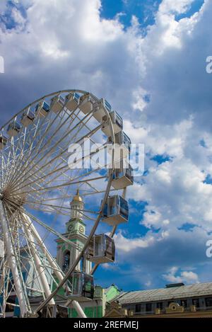 Grande roue sur la place Kontraktova à Kiev, Ukraine. Old Tower et Ferris Wheel. Nouvelle grande roue sur la place dans l'après-midi. Banque D'Images