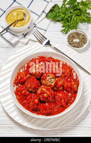 Boulettes de jambon de l'Iowa de bœuf haché, jambon haché et chapelure de craquelins avec un glaçage de sucre brun de tomate dans un bol blanc sur une table en bois blanc avec moutarde, vertic Banque D'Images