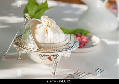 Fromage burrata dans des plats anciens avec des framboises rouges et jaunes. Banque D'Images