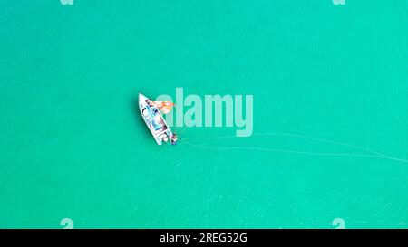 Vue d'en haut de l'eau de mer claire avec le personnel et les touristes se dirigeant vers le bateau après avoir terminé le parachute ascensionnel. Banque D'Images