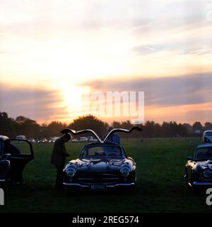 Le soleil se lève sur les amateurs de voitures anciennes préparant leur Mercedes-Benz 300 SL, Grand Tourer Gullwing Sports coupé 1955 pour une journée de Goodwood Revival. Banque D'Images