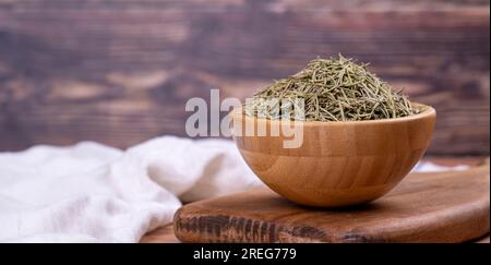 Feuilles de romarin aux herbes séchées. Assaisonnement sec au romarin sur fond de bois. Épices et herbes pour la cuisine, herbes de provence. Espace de copie. Espace vide pour le texte Banque D'Images