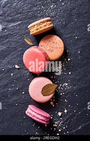 Macarons colorés sur un fond de marbre noir vu de dessus Banque D'Images