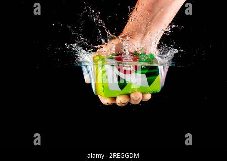 Londres, Royaume-Uni, 24 juillet 2023 : une boîte de 7 poses tenue dans une main éclaboussant dans l'eau sur un fond noir Banque D'Images