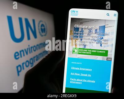 Personne tenant un téléphone portable avec le site Web du Programme des Nations Unies pour l ' environnement (PNUE) à l ' écran devant le logo. Concentrez-vous sur le centre de l'écran du téléphone. Banque D'Images