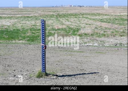 PAYS-BAS, Frise, Holwerd, mer du Nord, mer des wadden, vasières, gare maritime vers Ameland, indicateur de niveau d'eau / NIEDERLANDE, Friesland, Holwerd, Wasserstandsanzeiger, Hintergrund Fährstation zur Insel Ameland im Wattenmeer Banque D'Images