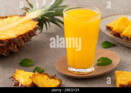 Smoothie frais délicieux jus d'ananas, boisson froide dans une tasse en verre sur fond de table gris. Banque D'Images