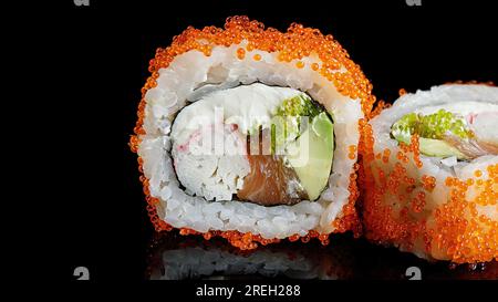 Roul de sushi au saumon, fromage à la crème, crabe, avocat et caviar tobiko, sur un miroir noir Banque D'Images