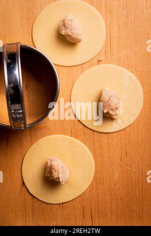 Faire des pâtes et des tortellini à la maison sur un rack en bois et une machine à pâtes chromées Banque D'Images