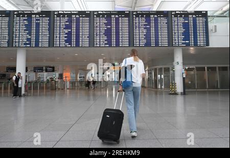 Munich, Allemagne. 28 juillet 2023. Une voyageuse marche vers sa porte dans le terminal 2 de l'aéroport de Munich. Les avions volent le dernier jour d'école avant les vacances d'été en Bavière. Crédit : Felix Hörhager/dpa/Alamy Live News Banque D'Images