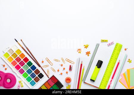 Retour à l'école. Papeterie différente sur fond de table blanc, mise à plat. Espace pour le texte. Vue de dessus. Fournitures colorées, papier vierge, maquette d'éducation. Banque D'Images