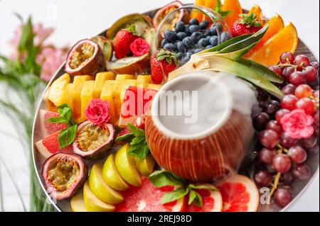 Assortiment de fruits crus et de baies sur l'assiette, sur la table blanche Banque D'Images