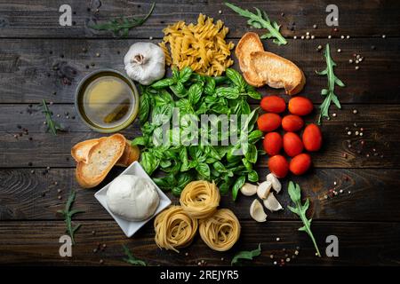 Ingrédients alimentaires italiens, mozzarella fraîche, bruschetta, tagliatelle et fusilli, feuilles de basilic, tomates, ail, roquette, huile d'olive et poivre Banque D'Images