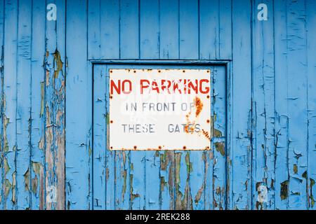Un vieux et usé pas de parking devant ces portes signe sur une porte bleue Banque D'Images