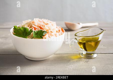 Bol en céramique blanche avec choucroute maison. À côté, il y a un bateau à sauce avec de l'huile d'olive. Le plat est décoré de persil. Gros plan sur une photo Banque D'Images