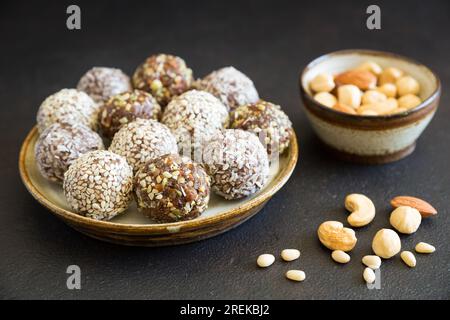 Boules énergétiques crues maison de bonbons avec amande, noix de cajou, beurre de cacahuète et noisettes sur la plaque sur le fond sombre en gros plan. En-cas bio. Banque D'Images