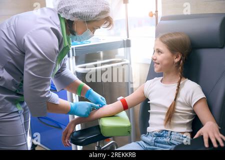 Le docteur féminin prend le sang d'une veine de fille mignonne Banque D'Images