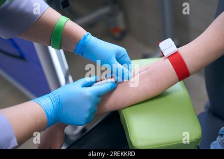 Infirmière en gants de protection prélève le sang du patient pour analyse Banque D'Images