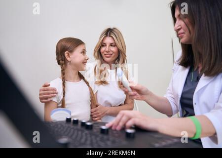 Médecin diagnosticien communique avec un petit patient dans la salle d'échographie Banque D'Images