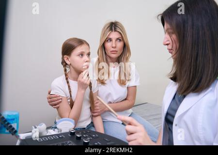 Femme inquiète avec sa fille au rendez-vous des médecins à la clinique Banque D'Images