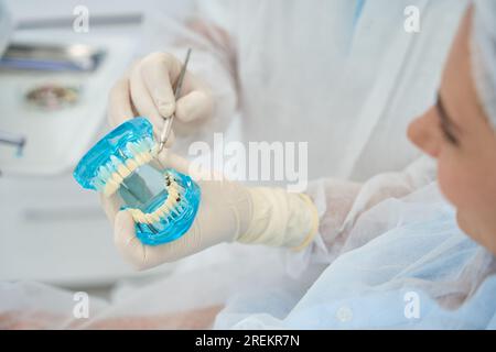 Docteur orthodontiste montre le modèle de patient avec des implants dentaires et des facettes Banque D'Images