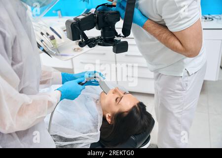 Médecin avec l'aide d'un assistant photographie les dents des patients Banque D'Images