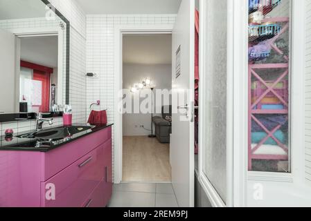 Salle de bain complète avec meuble lavabo rose avec comptoir lavabo noir brillant et miroir avec cadre noir Banque D'Images