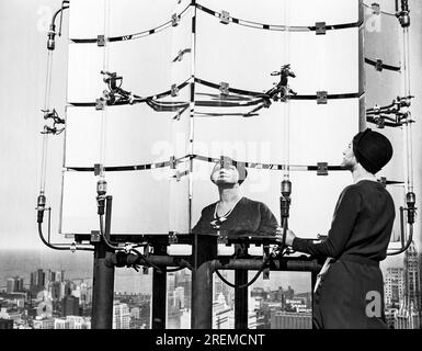 Chicago, Illinois : 4 septembre 1930 Une femme examine le «feu à éclats solaires» au sommet du nouveau bâtiment LaSalle-Wacker. Les miroirs mesurent cinq pieds de haut et trois pieds de large et réfléchissent les rayons du soleil pendant la journée et reflètent les néons rouges la nuit. Banque D'Images