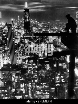 New York, New York : 18 novembre 1932 Un ouvrier fait une pause pour admirer l'Empire State Building nouvellement achevé et les gratte-ciel de New York. La vue est probablement du sommet du bâtiment RCA dans le Rockefeller Center qui a été achevé en 1933. Banque D'Images