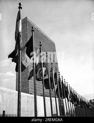 New York, New York : avril, 1957 drapeaux représentant les pays membres de la vague de l'ONU en exposition permanente devant le bâtiment de l'Assemblée générale dans le centre-ville de Manhattan. Banque D'Images