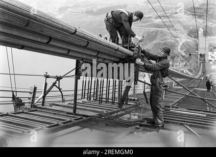 San Francisco, Californie : c. 1936 travailleurs sur les passerelles rassemblant les câbles pendant la construction des câbles du Golden Gate Bridge. Banque D'Images