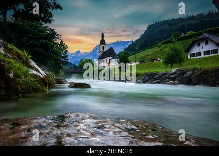 Paysage photographié, église à Berchtesgaden. Rivière et montagnes au coucher du soleil Banque D'Images