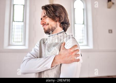 Homme, escrime et blessure, douleur à l'épaule ou accident après l'entraînement, exercice et entraînement en club. Escrimeur, problème de bras et athlète atteint d'arthrite Banque D'Images