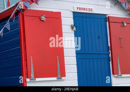 Rouge, blanc et bleu - détail coloré d'une cabane de plage sur Westward Ho! Front de mer surplombant la plage et l'estuaire de Torridge. Banque D'Images